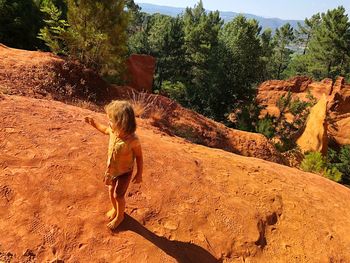 Girl standing on rock formation during sunny day