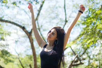 Young woman with arms raised in forest