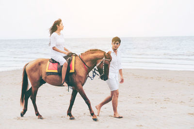 Full length of young woman riding horse on beach