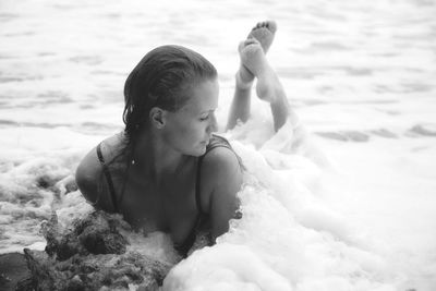 Young woman lying in surf at seashore