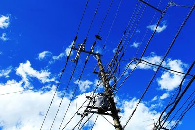 Low angle view of electricity pylon against blue sky