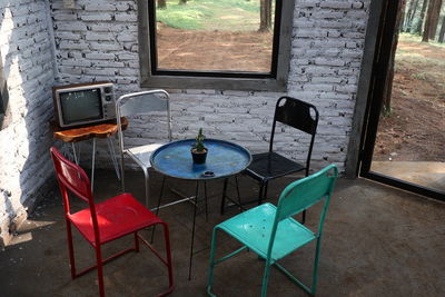 High angle view of empty chairs and table against wall