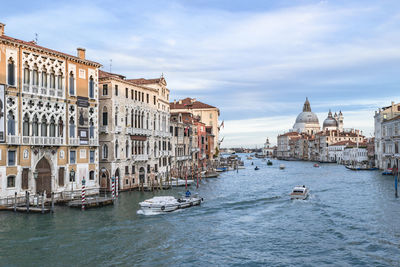 Buildings by river against cloudy sky