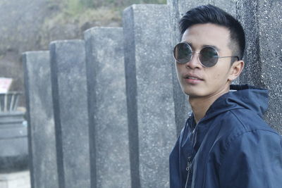 Portrait of young man wearing sunglasses against columns