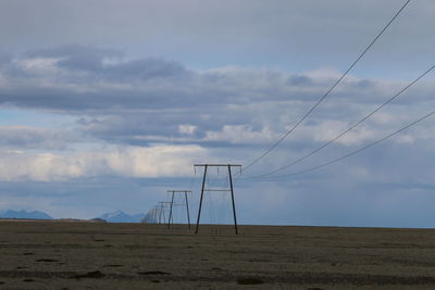 Electricity pylon on land against sky