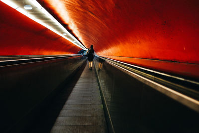 Rear view of people walking in illuminated tunnel