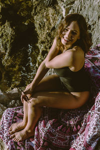 Woman sitting on rock formation at beach