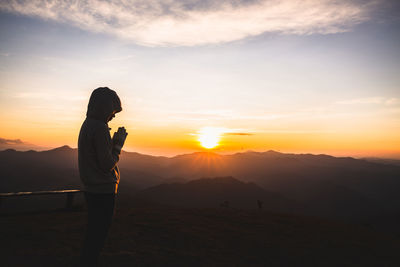 Silhouette woman standing on mountain against sky during sunset
