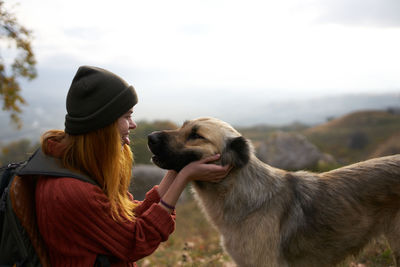 Side view of woman with dog against sky