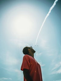 Low angle view of person against vapor trail in sky