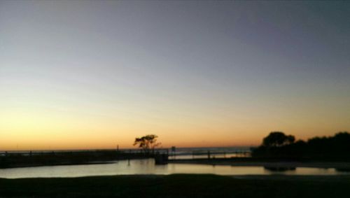 Scenic view of lake against clear sky at sunset