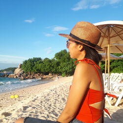 Young woman wearing sunglasses on beach against sky