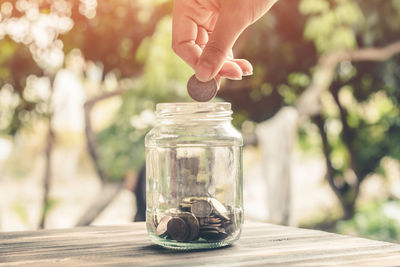 Close-up of hand holding glass jar on table