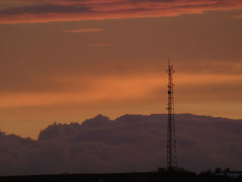 Silhouette of communications tower against sky during sunset