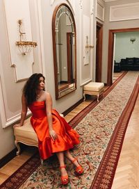 Full length of woman sitting at entrance of building