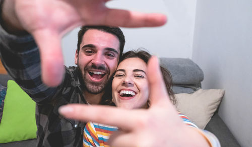 Portrait of cheerful young couple making finger frame