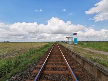 Railroad track amidst field against sky