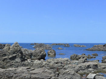 Rocks on beach against clear blue sky