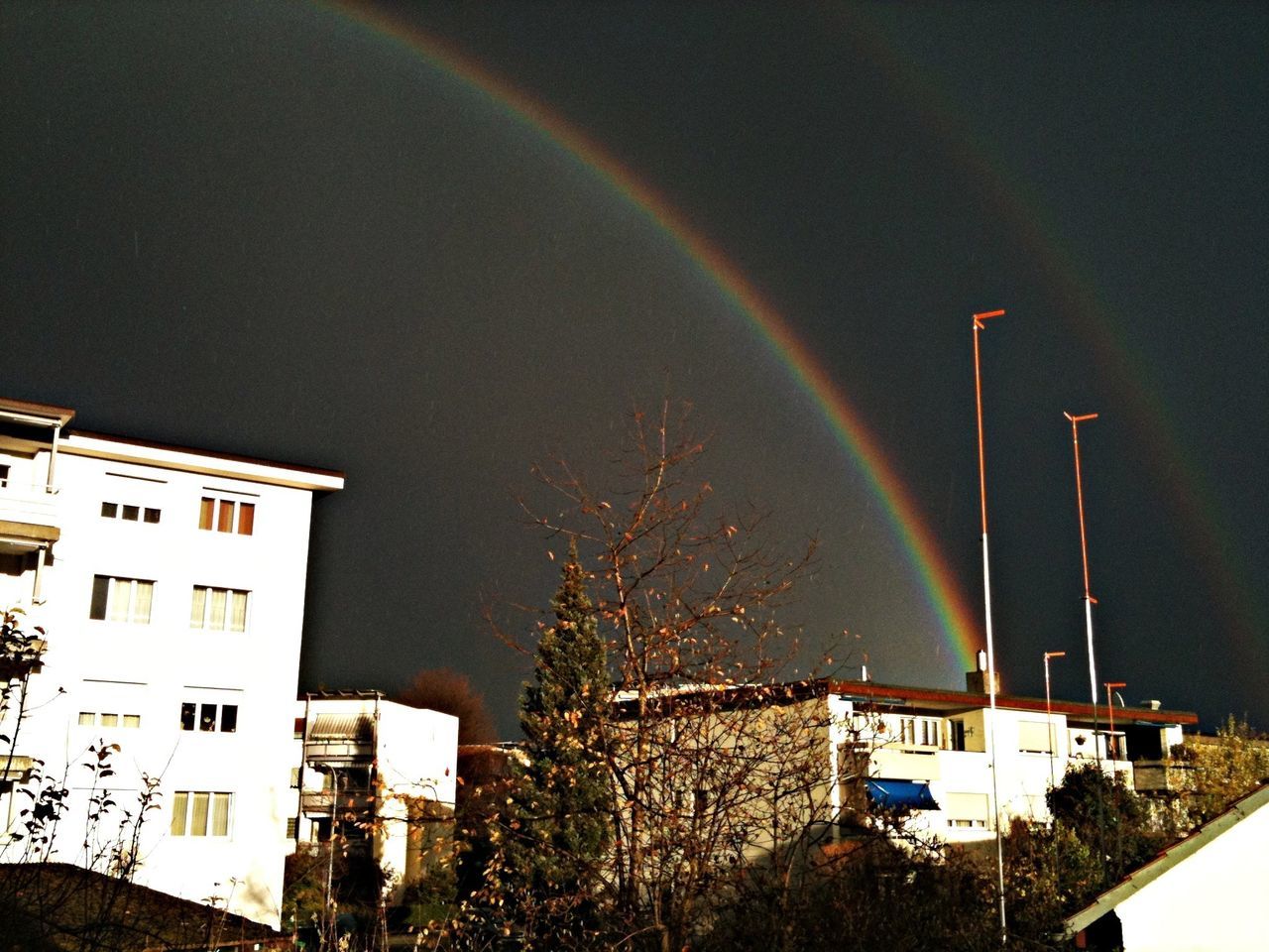 building exterior, architecture, built structure, sky, night, house, rainbow, residential structure, residential building, low angle view, weather, outdoors, building, tree, no people, illuminated, multi colored, city, residential district, nature