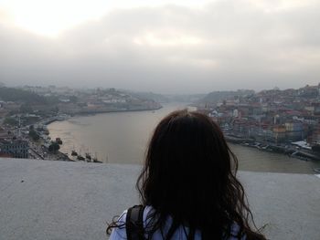 Rear view of woman in city against sky