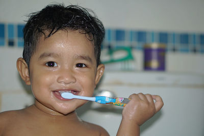 Portrait of shirtless boy brushing teeth in bathroom