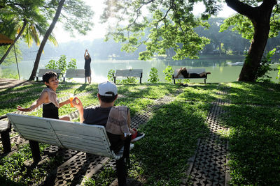 Boys sitting on grass against trees