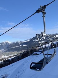 Ski lift over snowcapped mountains against sky