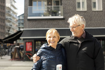 Smiling senior couple standing against building