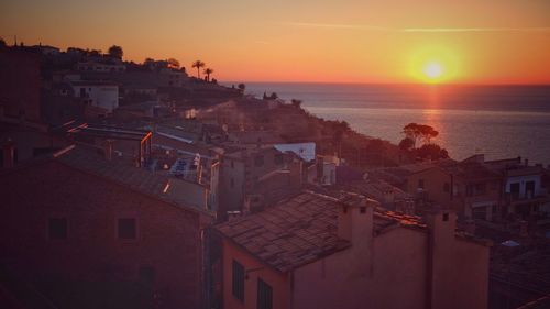 High angle view of town by sea during sunset