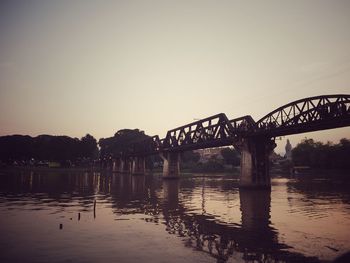 Bridge over river against clear sky during sunset