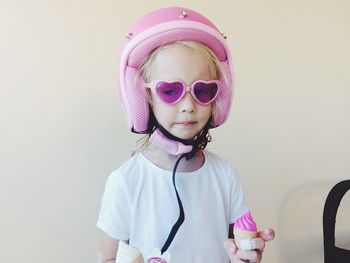 Cute girl in sunglasses wearing helmet against wall