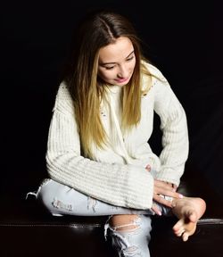 Smiling girl sitting against black background