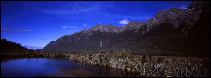 Scenic view of lake and mountains against blue sky