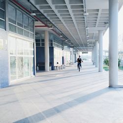 Man riding bicycle in corridor of building