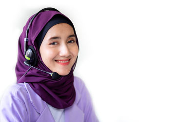 Portrait of smiling woman wearing hijab against white background