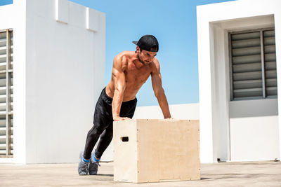 Full length of shirtless man exercising outdoors