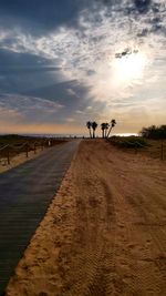 People riding bicycle on road against sky during sunset