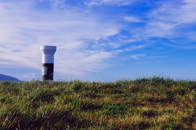 Lighthouse on field against sky