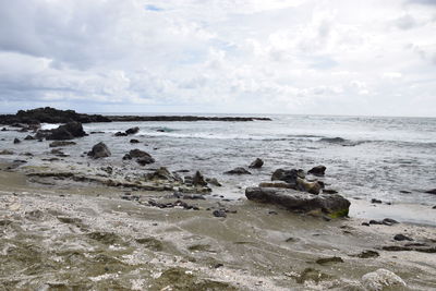 Scenic view of rocks on beach against sky