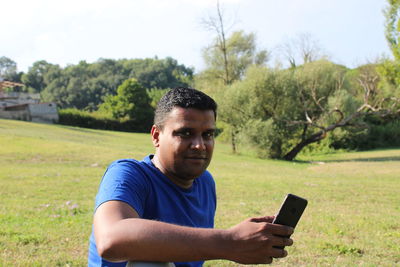 Portrait of young man using mobile phone on land