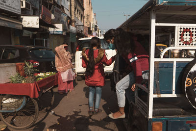 Rear view of people standing on street in city