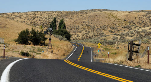 Empty road against mountains on sunny day