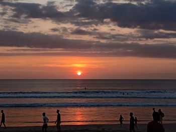 Silhouette people on beach against sky during sunset