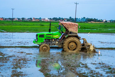 Tractor on agricultural field against clear sky