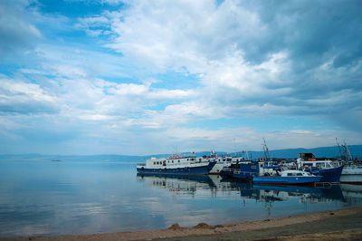 View of boats in sea against cloudy sky