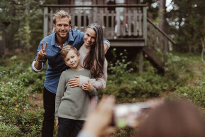 Portrait of smiling family taking pictures while standing in backyard