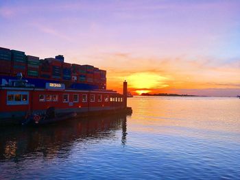 Building by sea against sky during sunset