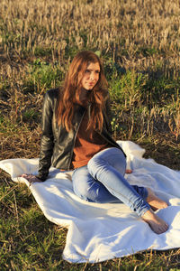 Portrait of smiling young woman sitting on land