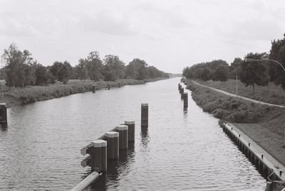 Wooden posts in lake against sky