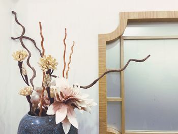 Close-up of white flowering plant in vase against wall